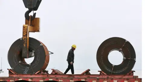 AFP/Getty This photo taken on May 19, 2018 shows a worker preparing to lift a roll of steel with a crane at a shipyard in Nantong in China's eastern Jiangsu province.