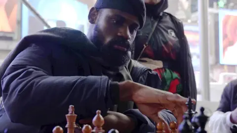 AP In this screen grab taken from video, Tunde Onakoya, 29- years old, a Nigerian chess champion and child education advocate, play a chess game in Times Square, New York, Thursday, April, 18, 2024. A Nigerian chess player and child education advocate is attempting to play chess nonstop for 58 hours in New York City's Times Square to break the global record for the longest chess marathon and raise $1m for the education of children across Africa