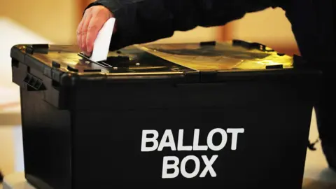 Ballot box with hand placing vote slip