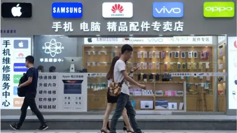 Getty Images People walking past a phone shop in China