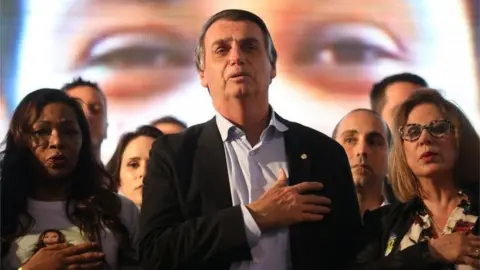 Reuters Presidential candidate Jair Bolsonaro listens to the national anthem during a meeting with women in Porto Alegre on 30 August, 2018.