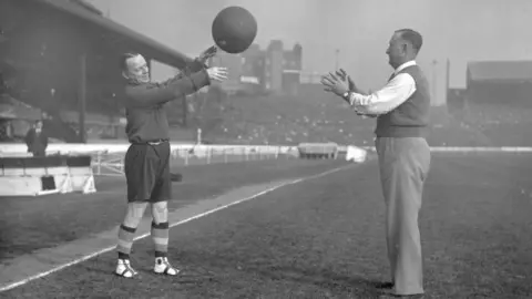 HF Davis/Topical Press Agency/Getty Images AJ Jewell training with a medicine ball with Charlie Harris