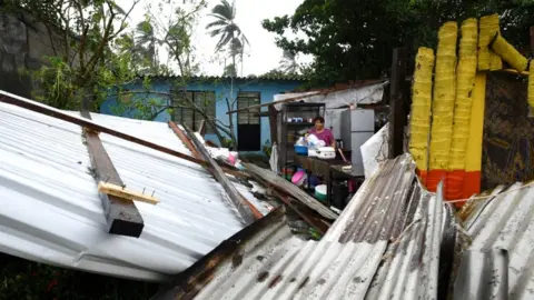 Reuters A woman stands amidst the debris of her home which was destroyed when Hurricane Grace slammed into the coast with torrential rains, in Costa Esmeralda, near Tecolutla, Mexico, 21 August 2021