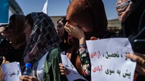 Getty Images One woman weeps during a protest against the news of an all-male interim government in Afghanistan