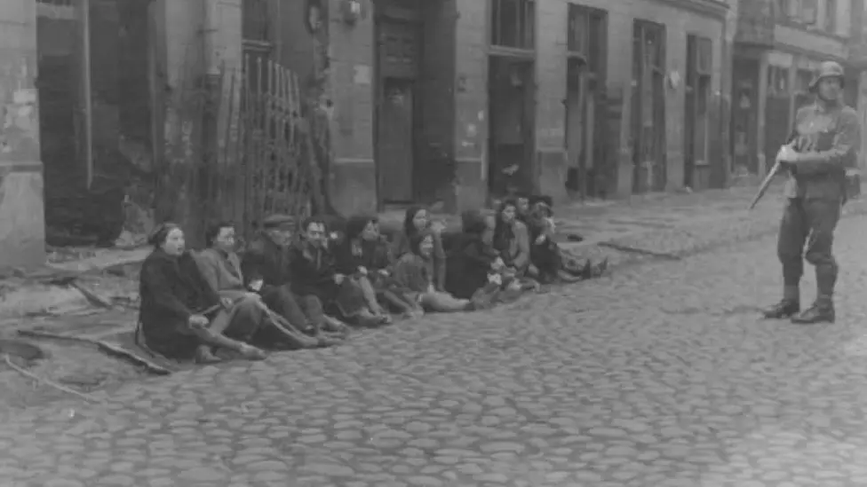 Unknown, via Wiki Commons A soldier stands guard of people on a road