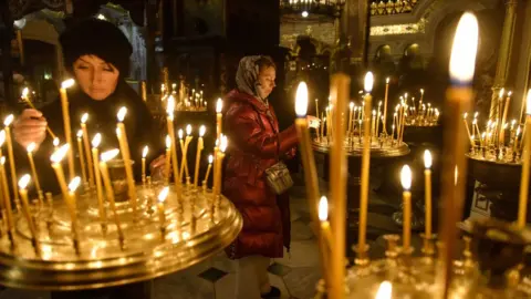 EPA Ukrainian women light candles during a service