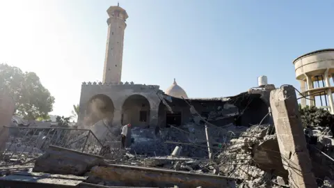 Reuters A Palestinian man inspects a mosque damaged in an Israeli strike, in Deir al-Balah, central Gaza (25 August 2026)