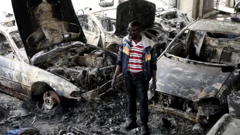 Reuters Man inspecting fire damaged car lot