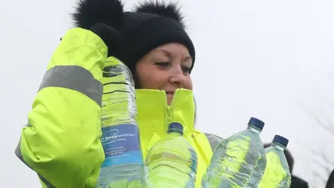 PA A volunteer from South East Water helps hand out bottles of water in Lenham, Kent