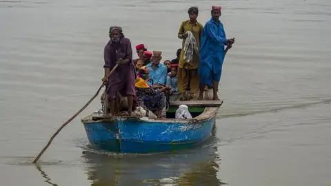 Getty Images Stranded people are evacuated on boats in Sukkur