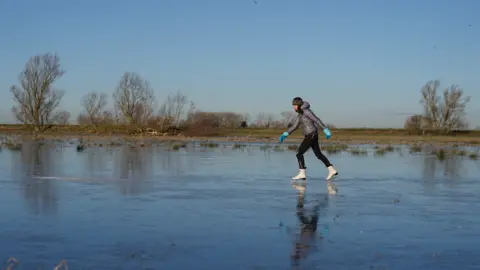 PA Media Fen skaters on a frozen lake in Upware, Cambridgeshire