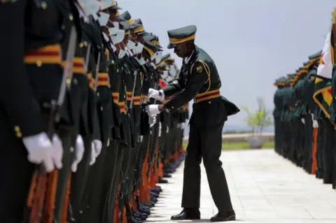 EPA A member of the Presidential Guard adjusts the uniform of his colleague before the Zimbabwean President Emmerson Mnangagwa arrived to deliver the State of The Nation Address and officially open the fifth session of the Ninth Parliament in the newly built Parliament building in Mount Hampden, Zimbabwe, 23 November 2022