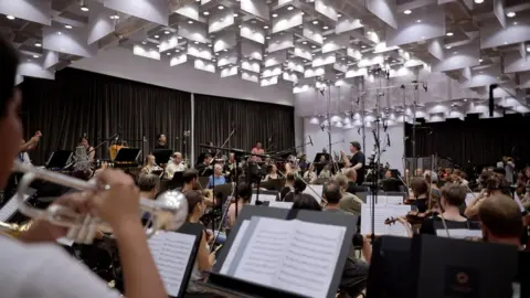 Máximo Garcia/La Caixa Foundation Here, Gustavo Dudamel leads rehearsals with the orchestra behind the recordings in the films