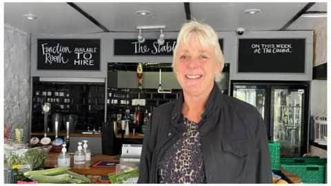 BBC Smiling woman in front of shop counter