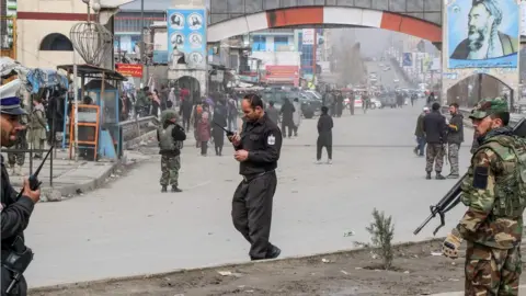 AFP Afghan security forces personnel stand guard on a road near the site of a gun attack that occurred during an event ceremony to mark the 25th anniversary of the death of Shiite leader Abdul Ali Mazari, in Kabul on March 6, 2020.