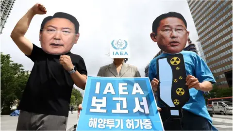 Chung Sung-Jun South Korean activists wearing masks of Japan's Prime Minister Fumio Kishida (R) and South Korea's President Yoon Suk Yeol (L) protest against the International Atomic Energy Agency's (IAEA) report on the Fukushima water release plan, at Gwanghwamun Square in Seoul on July 5, 2023.