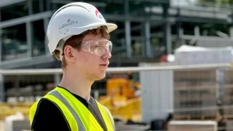 Blake Smith-Helps wearing hi-vis, a helmet and protective glasses on a construction site. 