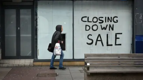 AFP A pedestrian walks past a boarded-up shop in Sunderland