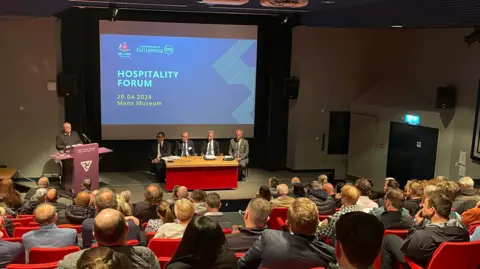 BBC People listening to a speech at the meeting