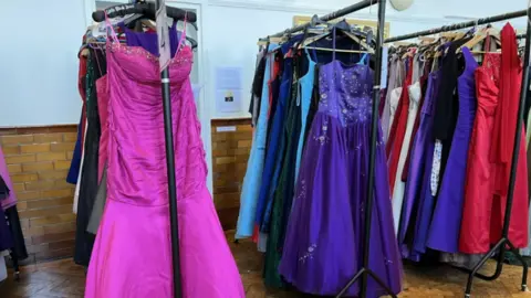 Emma Baugh/BBC Colourful prom dresses on a rack