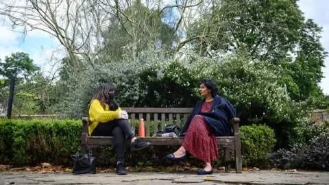 Getty Images Two friends sitting on a park bench