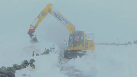 Digger clearing snow from road