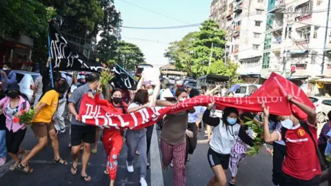 Protesters hold banners while fleeing military truck