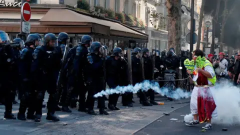 Getty Images A line of riot police firing tear gas at a protester