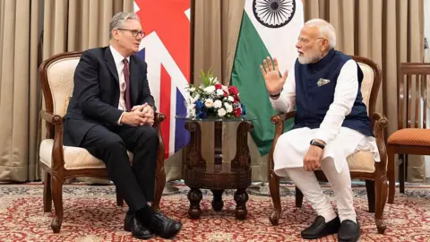 WPA Pool/Getty Images Prime Minister Sir Keir Starmer and Prime Minister of India Narendra Modi at a bilateral meeting in Mumbai, India in October 2025. Behind them are the flags of the two countries. Prime Minister Keir Starmer travelled along with representatives from British businesses, universities, and cultural institutions to promote the free trade agreement signed between the UK and India. 