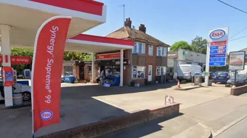 Google The front of an Esso petrol station forecourt, with a shop that has been built into the side of a detached home.