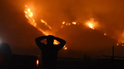 Getty   Man stands watching the fire burn