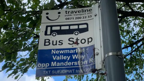 Shaun Whitmore/BBC Bus stop sign reads: Bus stop Newmarket, Valley Way, opp Manderston Rd