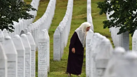 Getty Images A Srebrenica survivor kisses her son's gravestone