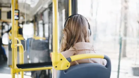 Getty Images Woman listens to headphones on the bus