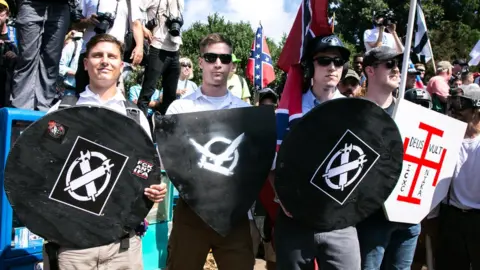 NurPhoto via Getty White nationalists hold shields with symbols on