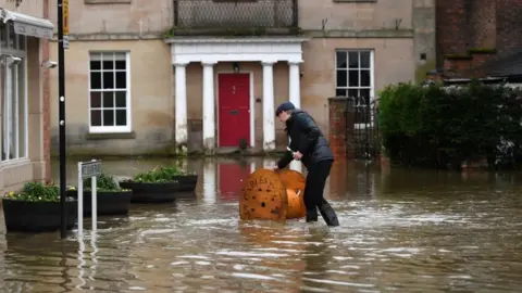 Getty Images Man wheeling drum through flood water in Shrewsbury