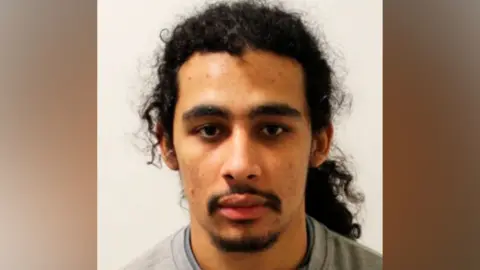 A close-up mugshot of Aderahman Boumzough wearing a grey crew-neck jumper over a dark undershirt, positioned against a plain white background.