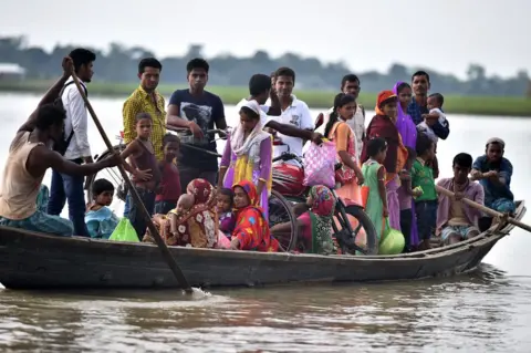 Getty Images Villagers in Assam travel by boat during floods in 2016