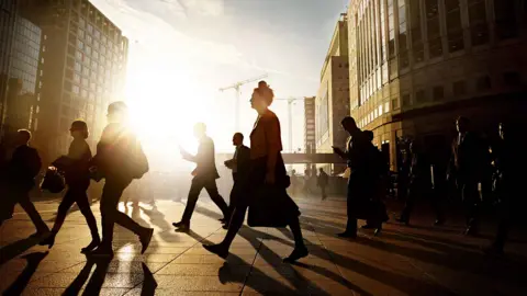 Getty Images People in outline walking through city of London at sunrise