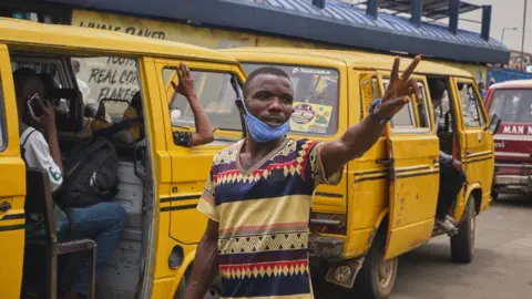 Getty Images A conductor stands in front of a Lagos danfo