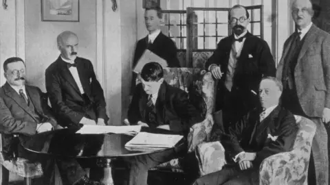 Topical Press Agency/Getty Images Michael Collins signing the Anglo-Irish Treaty on 6 December 1921