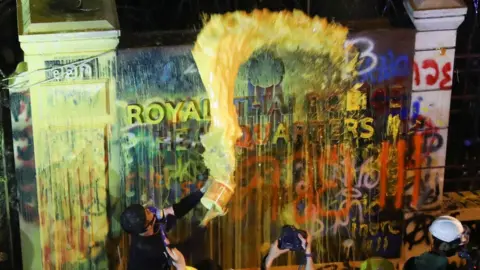 Reuters A demonstrator throws paint over a plaque with lettering on it in front of the police headquarters during a rally in Bangkok