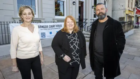 Liam McBurney NI Justice Minister Naomi Long (centre), with Open House founders Alison Gordon (left) and Kieran Gilmore (right), ahead of the opening of The Court House, in Bangor, Northern Ireland which has been repurposed from a Bangor Courthouse.