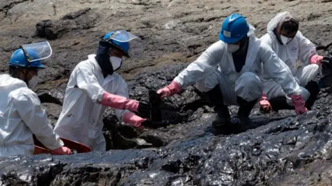 Getty Images Cleaning crews work to remove oil from a Peruvian beach