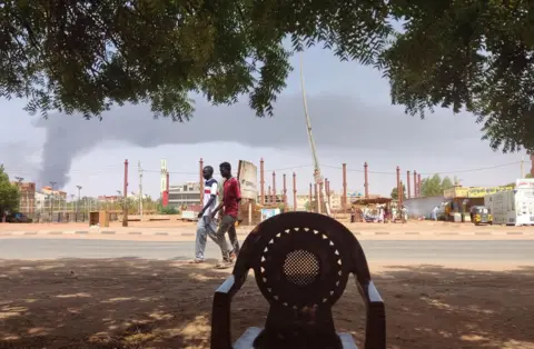 AFP Men walking down the street against a backdrop of smoke.