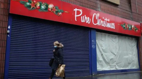 PA Media Woman walks past closed shop in Glasgow