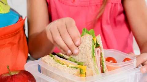 Getty Images Girl picking up sandwich from lunchbox