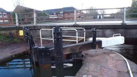 John Sadler The Star Lock on the Trent & Mersey Canal in Stone, Staffordshire, is seen after rebuilding work. Buildings are around the canal and there is a bridge above the lock.