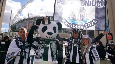 Owen Humphrey/PA Wires Two men and a women in Newcastle United strips with another person dressed as a giant panda. They are holding aloft a banner and Wembley Stadium can be seen in the background