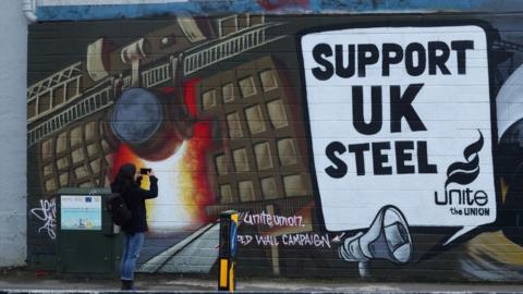 A woman photographs a Unite mural in Port Talbot